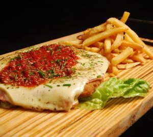 Escalope de pechuga de pollo "Origen" con salsa de tomate, jamón, mozzarella, patatas fritas.